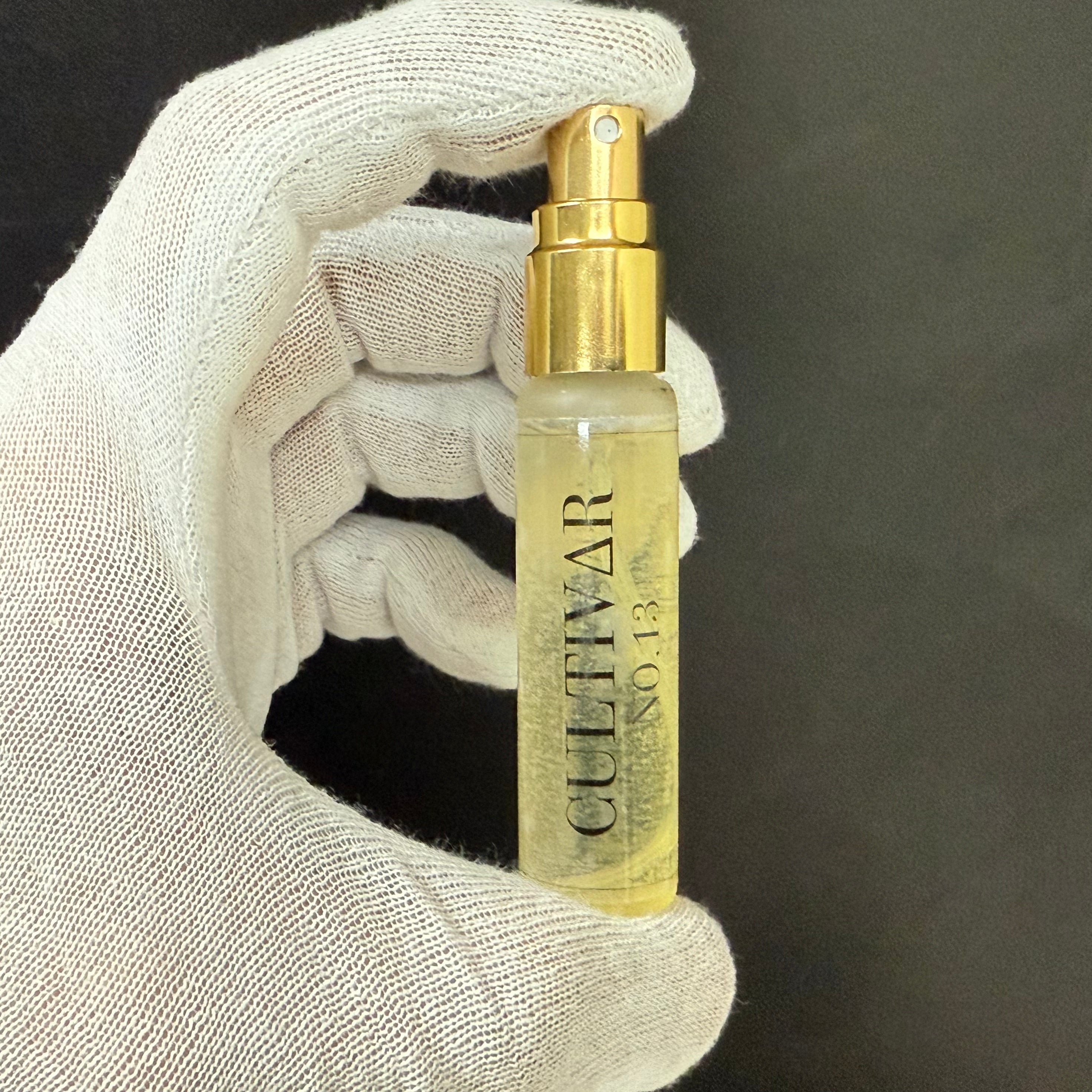 Hand holding a Cultivar No. 13 spray bottle against a dark background